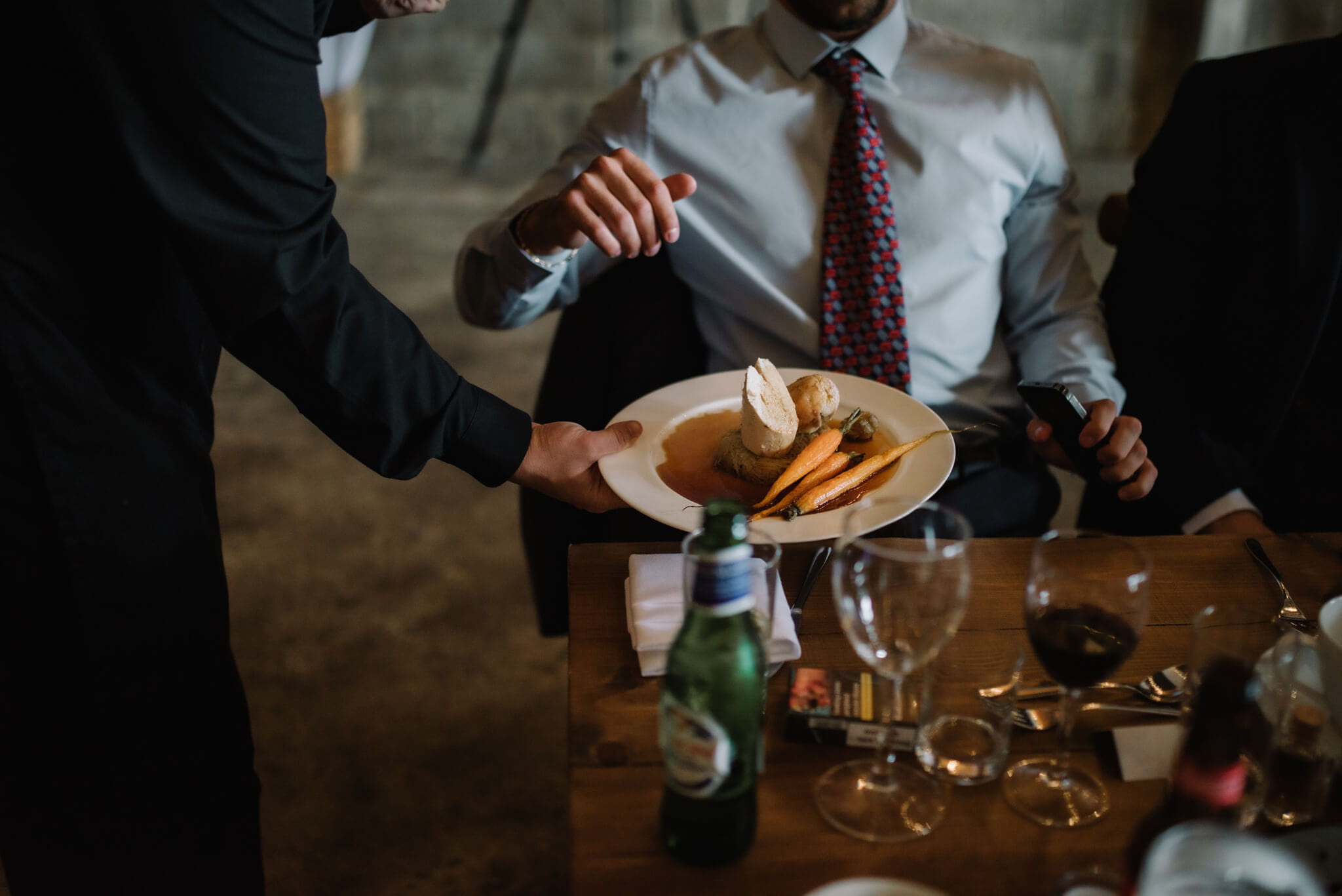Outside caterers serving a fine dining meal to a customer in a suit at dinner at a dinner table