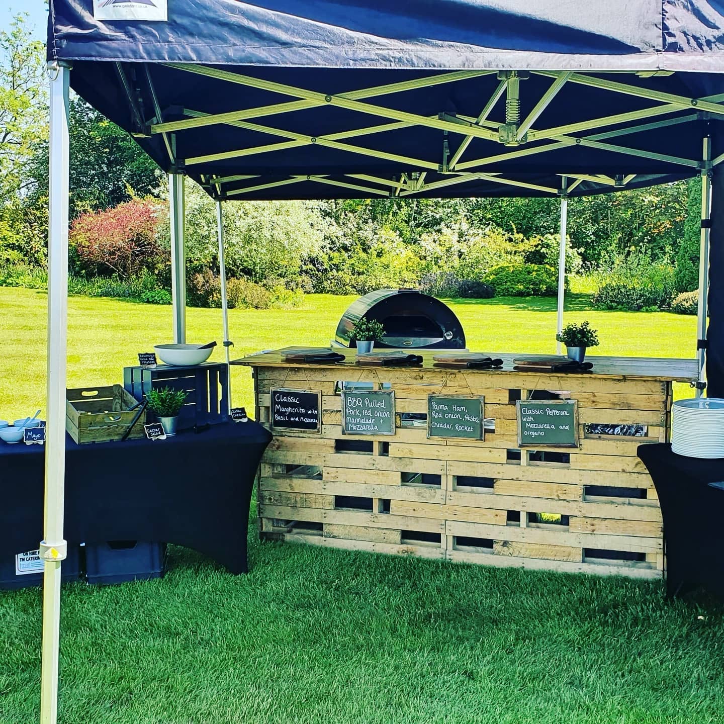 Engagement party catering featuring wood fired pizza food station in garden