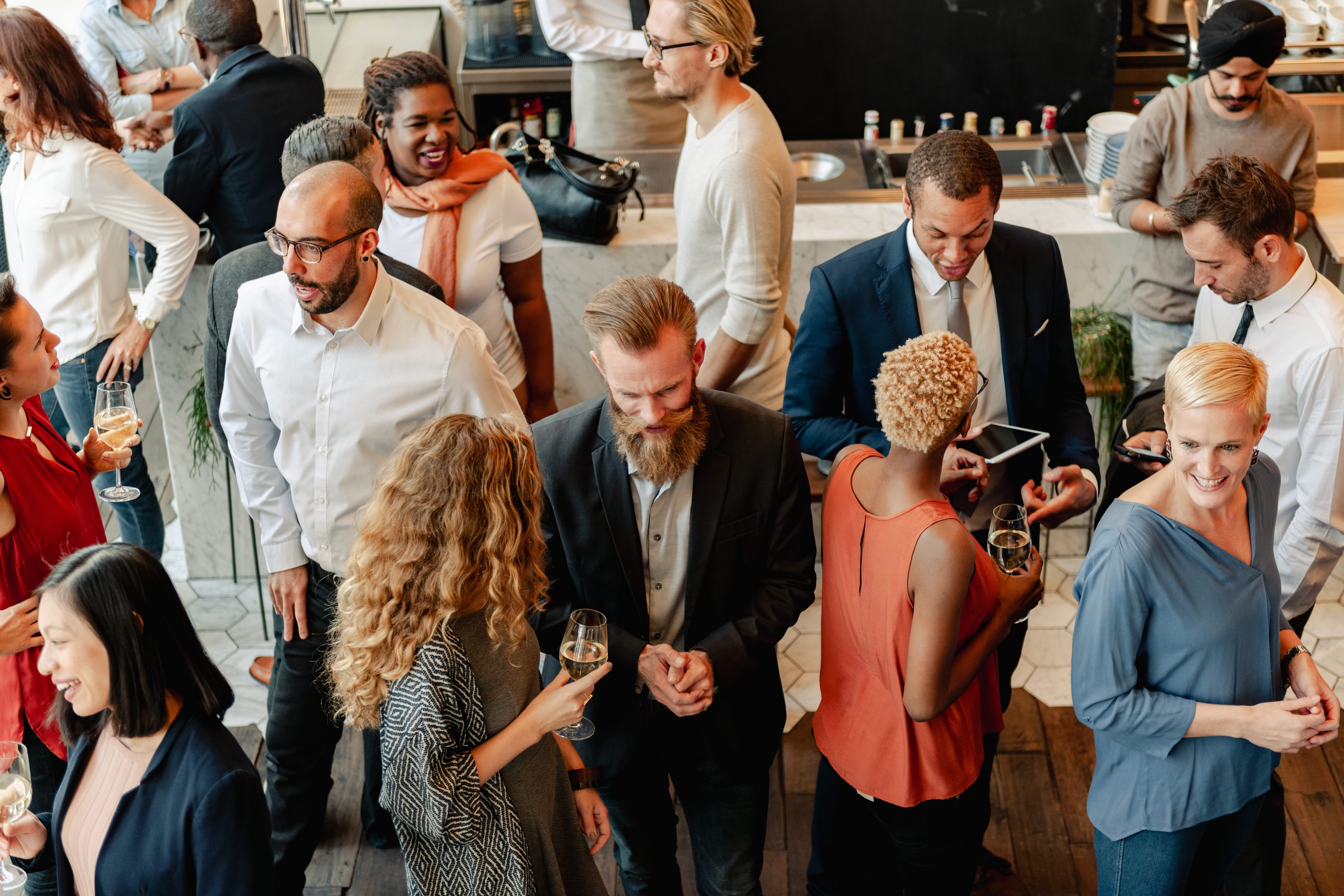 Diverse group of people at social event, mingling and chatting, after the group decided how to choose a corporate caterer.